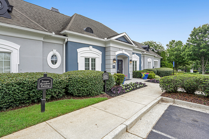Elegant apartment facade surrounded by lush greenery, featuring classic architecture and inviting entrance for future residents.