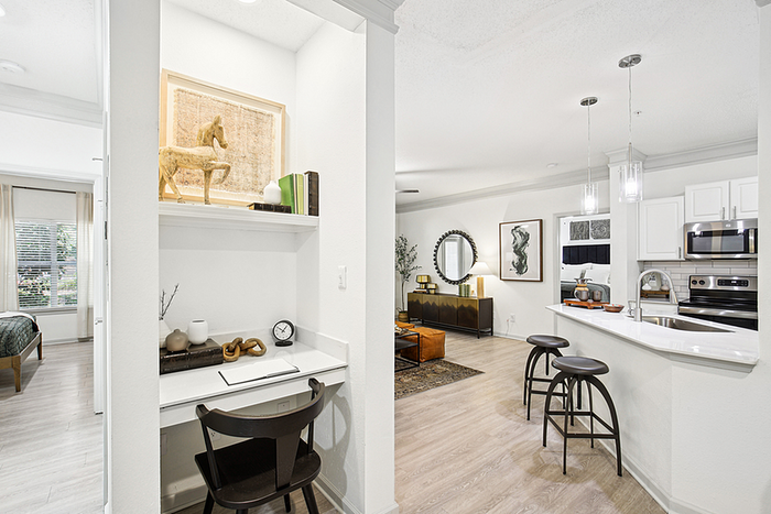 Modern apartment interior showcasing a stylish kitchen with sleek countertops, open-concept living room, and a cozy work nook.
