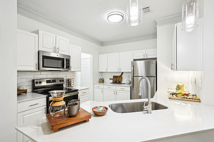 Elegant modern kitchen with stainless steel appliances, white cabinetry, and sleek countertops, offering a bright and stylish cooking space.