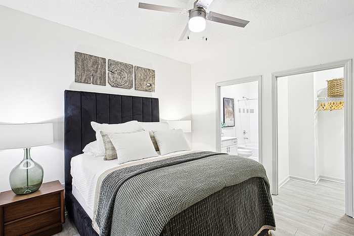 Bright and modern bedroom with plush bedding, stylish artwork, and access to a private bathroom and walk-in closet.