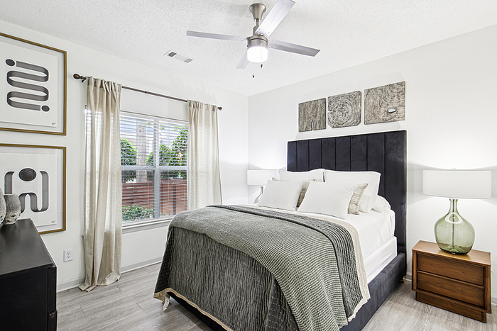 Elegant bedroom with a cozy bed, modern decor, soft lighting, and a large window with garden views.