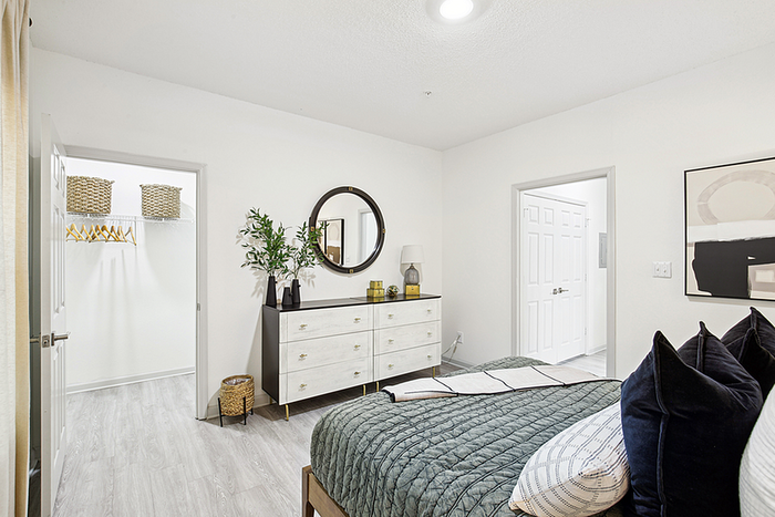 Bright and inviting bedroom with elegant decor, spacious walk-in closet, and stylish dresser, enhancing modern apartment living.