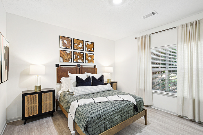 Elegant bedroom with modern decor, featuring a cozy bed, stylish artwork, and ample natural light from large windows.