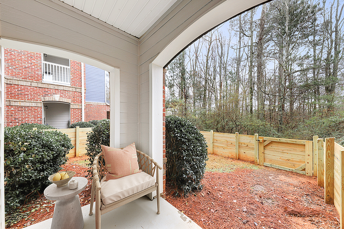 Charming patio with cozy seating overlooking a serene wooded area, perfect for relaxation.