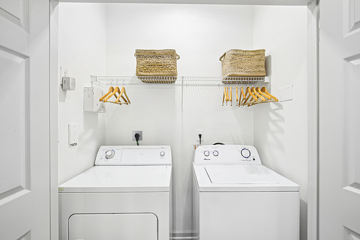Modern laundry nook with a sleek washer and dryer, featuring organized shelving and basket storage for convenience.