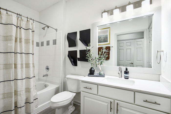 Elegant bathroom featuring a modern white vanity, stylish mirror with bright lighting, and minimalist decor.