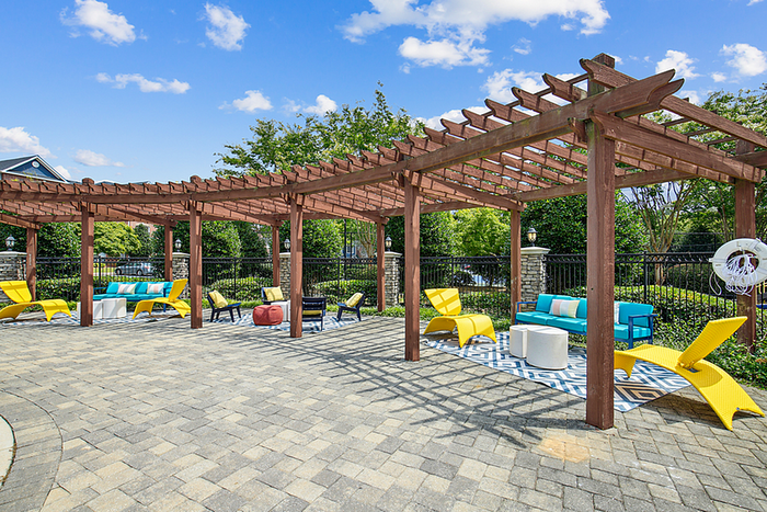 Charming outdoor patio with stylish wooden pergola, vibrant seating area, and lush greenery, perfect for relaxation.