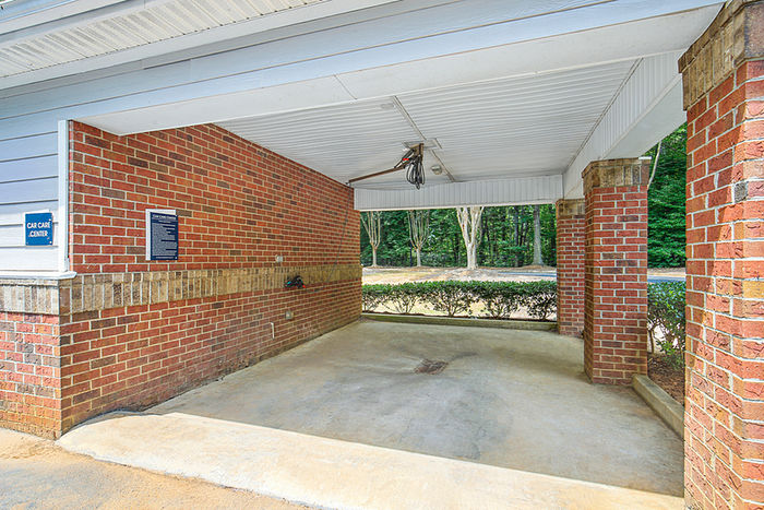 Inviting car care center with red brick walls and ample open space, surrounded by lush green trees.