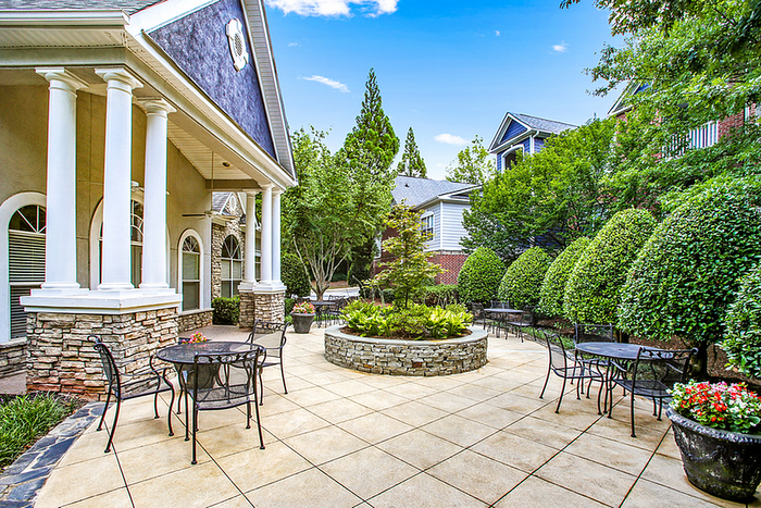 Inviting outdoor patio featuring elegant seating, lush greenery, and a charming stone facade.