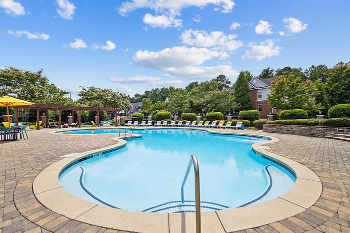 Inviting outdoor pool with sun loungers and shaded seating, perfect for relaxation on a sunny day.
