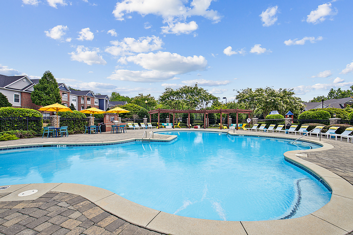 Luxurious outdoor pool area with clear blue water, surrounded by comfortable lounge chairs and vibrant yellow umbrellas, perfect for relaxation.
