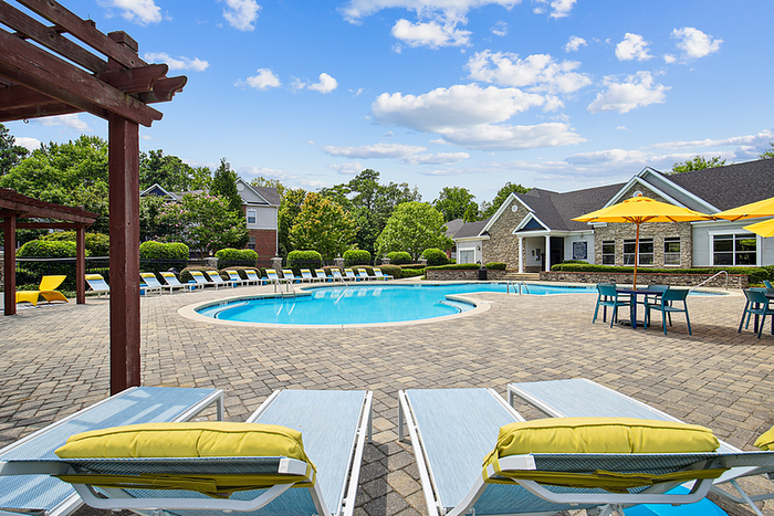 Inviting outdoor pool area with sun loungers, vibrant yellow umbrellas, and lush greenery, perfect for relaxation.