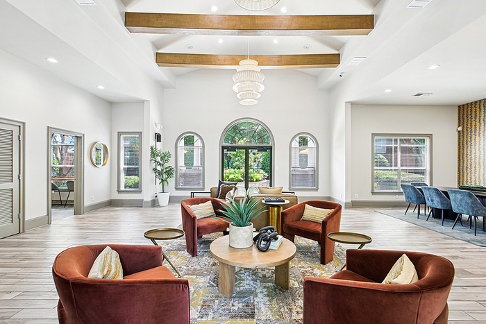 Bright and spacious apartment lounge featuring elegant design, modern furnishings, and abundant natural light through large arched windows.