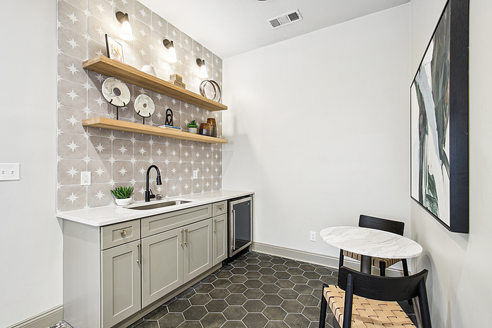 Chic kitchen nook with stylish backsplash, modern shelving, sleek cabinetry, and cozy dining setup.