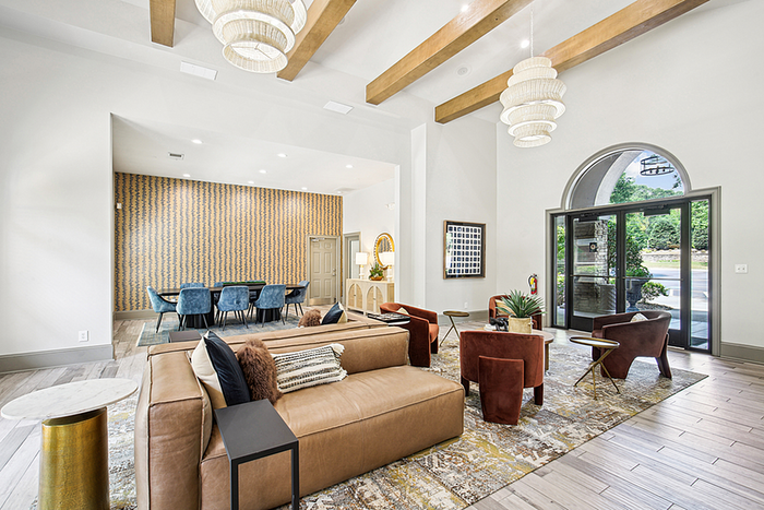 Luxurious modern lounge with stylish chandeliers, comfortable leather seating, and a vibrant dining area featuring contemporary blue chairs.