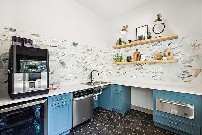 Chic kitchen with elegant blue cabinetry, modern appliances, and stylish open shelving against a marble-inspired backsplash.