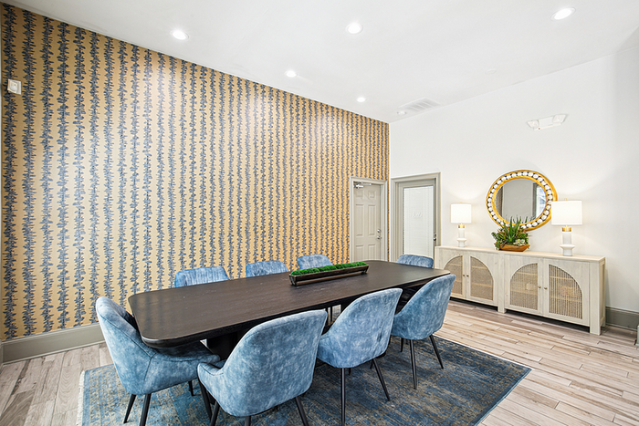 Elegant dining room with modern blue chairs, a sleek black table, and eye-catching patterned wallpaper, complemented by cozy lighting and stylish decor.