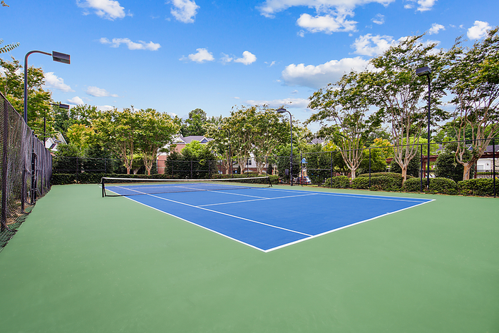 Vibrant outdoor tennis court set amidst lush greenery, perfect for sports enthusiasts and leisure living.