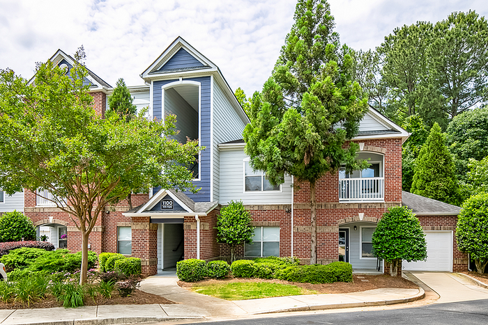 Charming brick apartment building with modern architecture, surrounded by lush greenery, offering a serene and inviting environment.