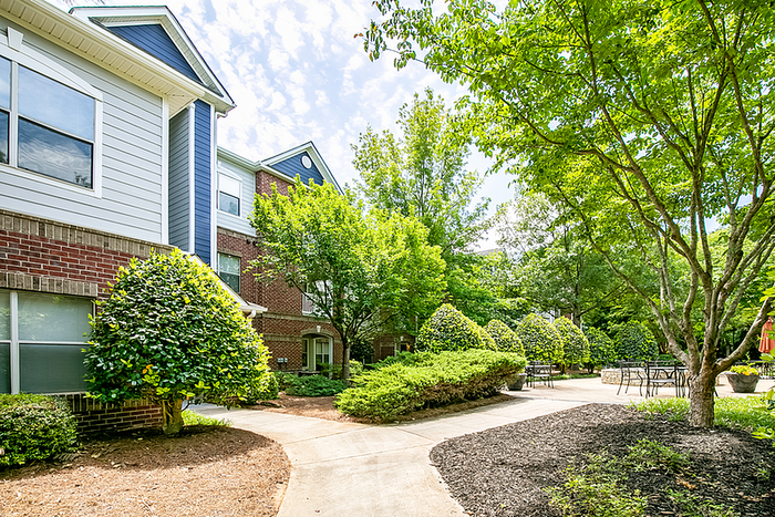 Charming apartment exterior with vibrant landscaping and inviting outdoor seating area.