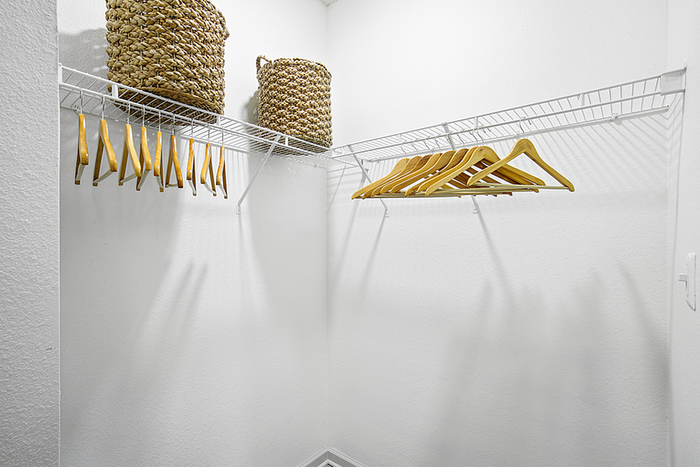 Spacious walk-in closet with modern wire shelving and elegant wooden hangers, ideal for organized storage.