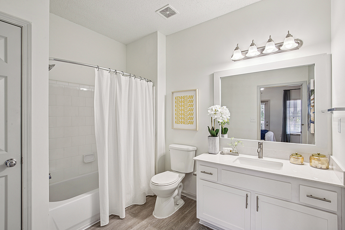 Bright and inviting bathroom with modern fixtures, large mirror, and elegant white cabinetry.