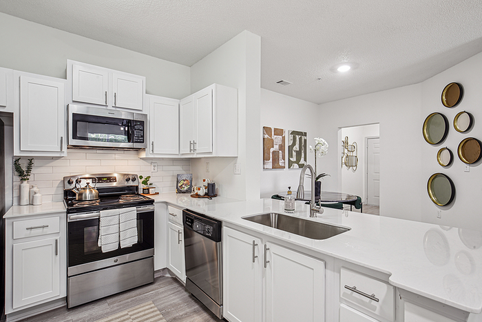 Modern kitchen with sleek stainless steel appliances, white cabinetry, and chic decor, offering a bright and inviting atmosphere.