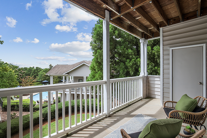 Charming balcony view overlooking a serene garden and pool area, perfect for relaxation and outdoor enjoyment.