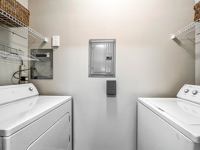 Modern laundry room featuring top-of-the-line washer and dryer, ample shelving for convenient storage, and sleek wall panels.
