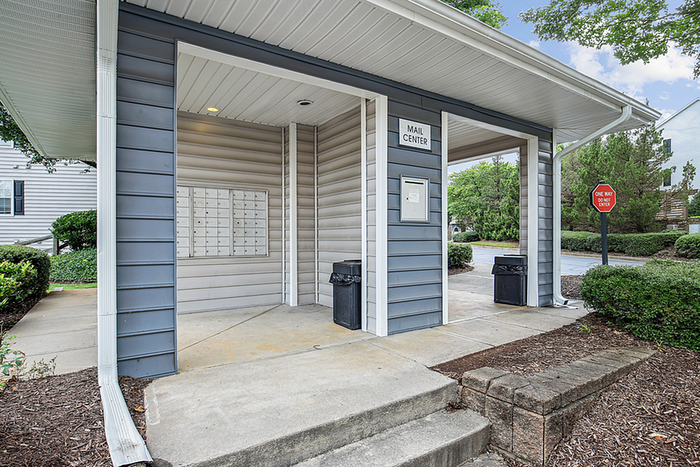 Charming community mail center with modern mailbox design, nestled in a lush green environment.