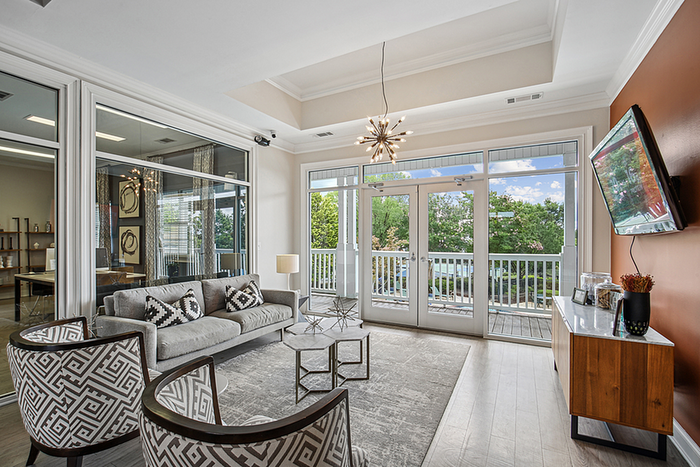 Bright and stylish clubhouse with modern decor, featuring large windows, chic seating, and a stunning view of lush greenery.