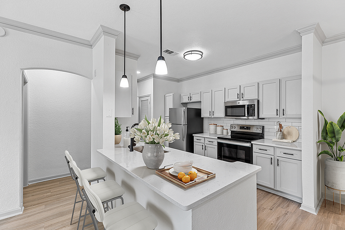 Bright and modern kitchen with sleek white cabinetry, stainless steel appliances, and elegant pendant lighting.