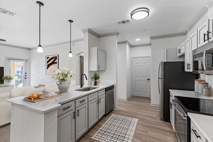Modern kitchen with elegant gray cabinetry, sleek stainless steel appliances, and an inviting open-concept design adjacent to a cozy living area.