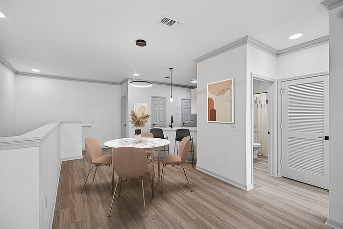 Modern apartment dining area with elegant round table, stylish chairs, and contemporary wall art under soft lighting.