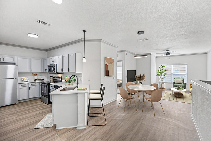 Modern open-concept living space featuring a sleek kitchen with stainless steel appliances and a stylish dining area flowing into a cozy living room with abundant natural light.