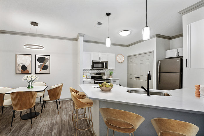 Chic open-plan kitchen and dining area with modern lighting, stylish bar stools, and contemporary artwork, showcasing elegant design.