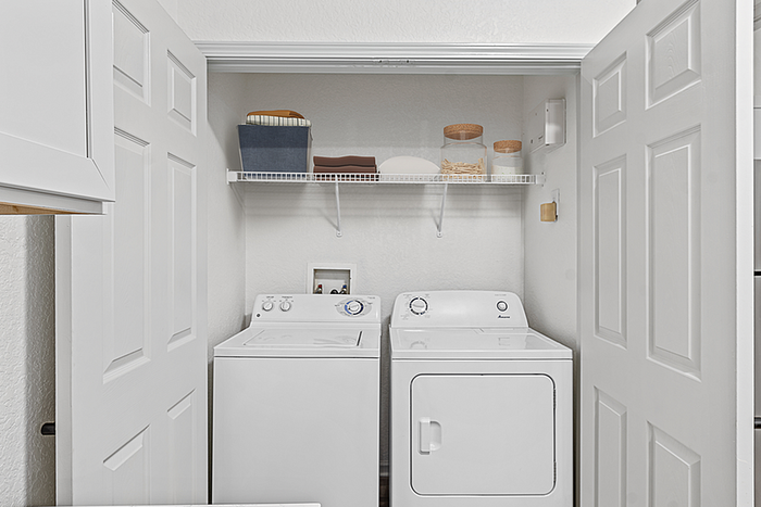 Chic and organized laundry closet featuring a modern washer and dryer, complete with stylish storage shelves and tasteful decor accents.