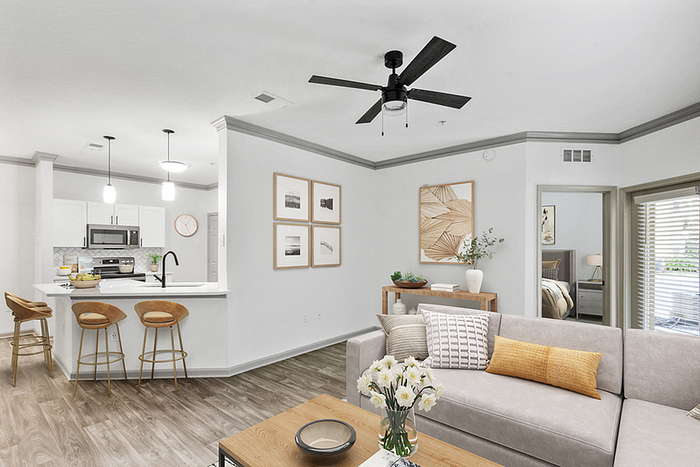 Modern open-concept living room and kitchen with sleek finishes, featuring stylish bar stools, elegant wall art, and abundant natural light.