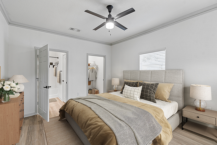 Inviting bedroom with elegant decor, featuring a plush bed, modern ceiling fan, and ample natural light.
