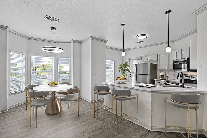 Sleek and modern kitchen with white cabinetry, stainless steel appliances, and a chic dining area bathed in natural light.