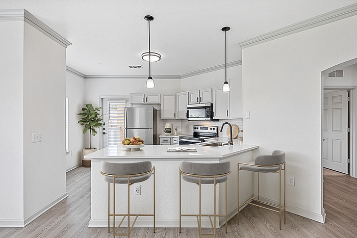 Elegant modern kitchen with sleek stainless steel appliances, stylish pendant lighting, and a cozy breakfast bar with plush seating.