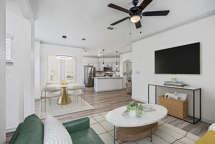 Modern open-plan living area featuring a stylish kitchen, cozy lounge with a green sofa, and a chic dining space with gold accents.