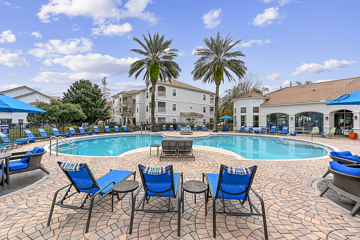 Luxurious outdoor pool area with palm trees, stylish lounge chairs, and a pristine swimming pool under a vibrant blue sky, perfect for relaxation and leisure.
