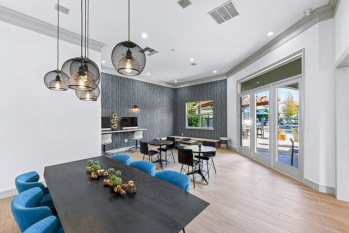 Modern clubhouse with elegant pendant lighting, stylish seating, and large windows overlooking a beautiful outdoor area.