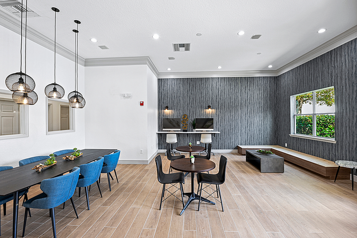 Elegant clubhouse space featuring a modern design with sleek lighting, chic blue seating, and a stylish dining area, perfect for social gatherings.