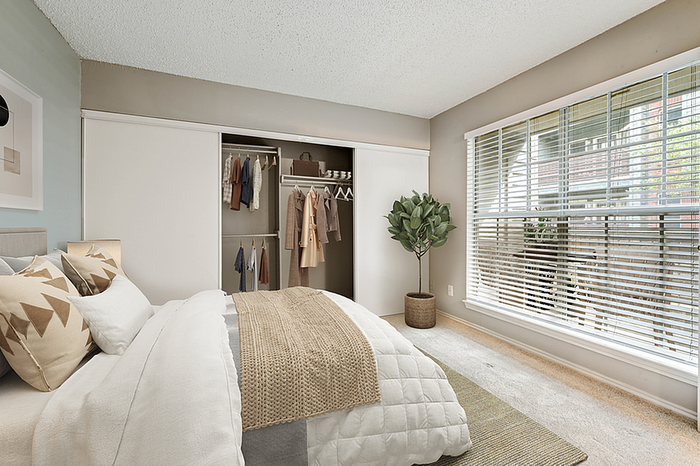 Inviting bedroom with a cozy bed, large wardrobe, and sunlit window overlooking greenery, offering comfort and style.