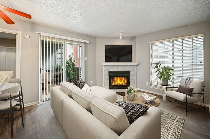 Inviting living room with cozy fireplace, modern furnishings, and natural light streaming through wide windows, opening to a charming outdoor patio.