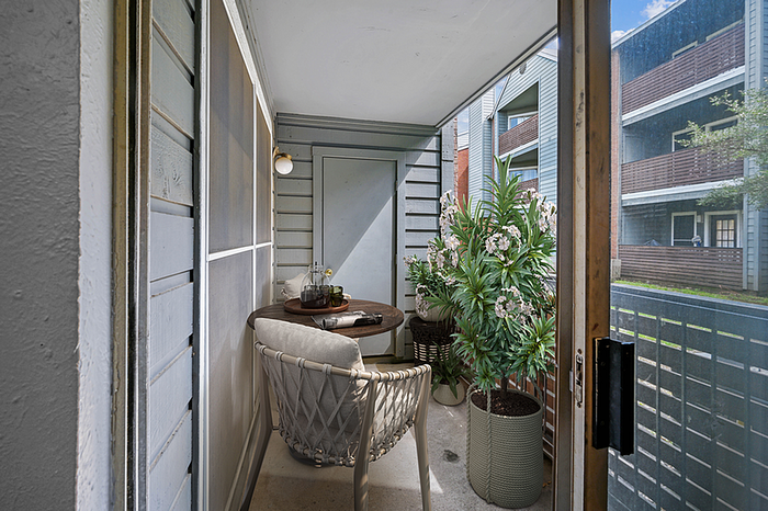 Charming apartment balcony with cozy seating, lush potted plants, and neighborhood views, perfect for relaxation.