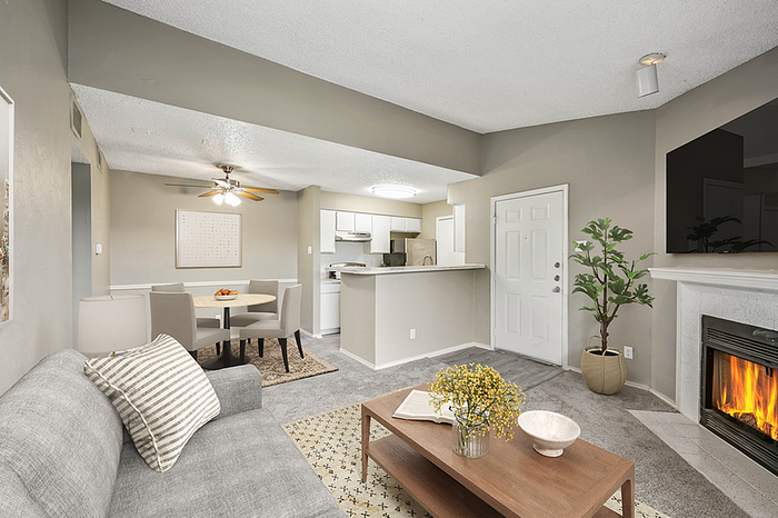 Elegant living space featuring an open-concept layout with cozy seating, a contemporary dining area, and a modern kitchen. Natural light enhances the warm ambiance, highlighting a fireplace and stylish decor.