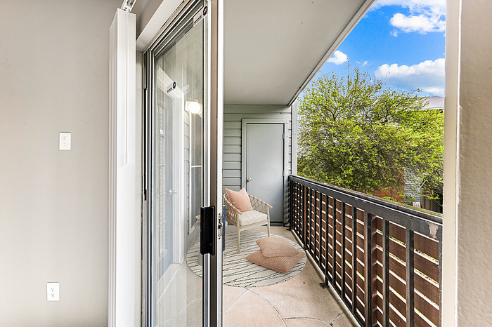 Inviting balcony with cozy seating and lush green views, perfect for relaxation under a clear blue sky.